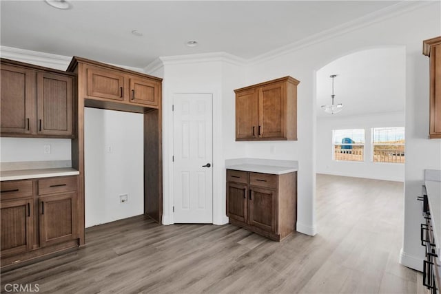 kitchen with pendant lighting, light hardwood / wood-style floors, ornamental molding, and an inviting chandelier