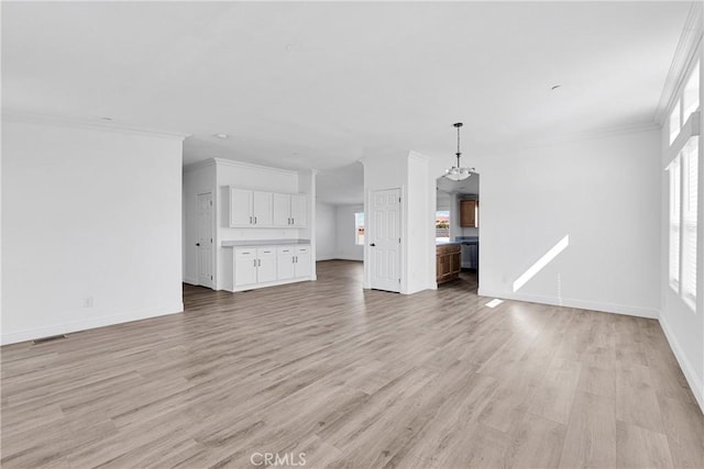 unfurnished living room featuring a chandelier, light hardwood / wood-style flooring, and ornamental molding