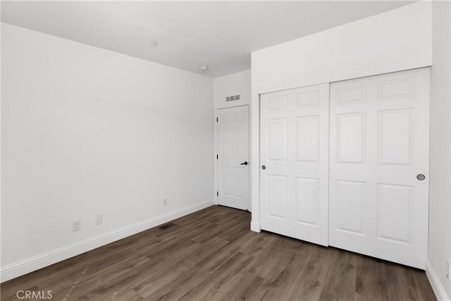 unfurnished bedroom featuring dark hardwood / wood-style flooring and a closet