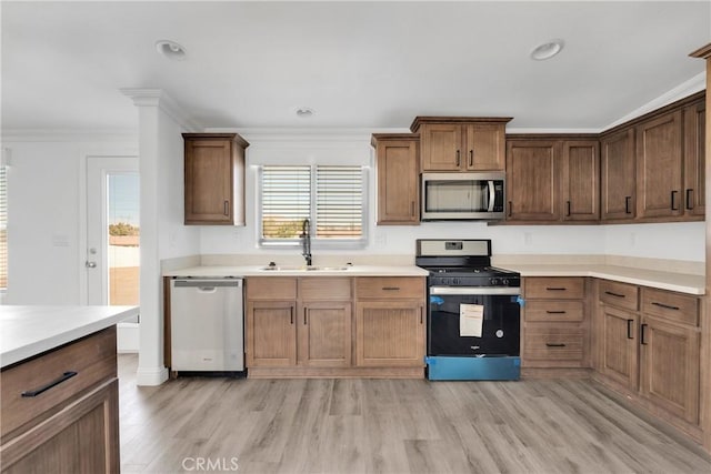 kitchen featuring crown molding, sink, appliances with stainless steel finishes, and light hardwood / wood-style flooring