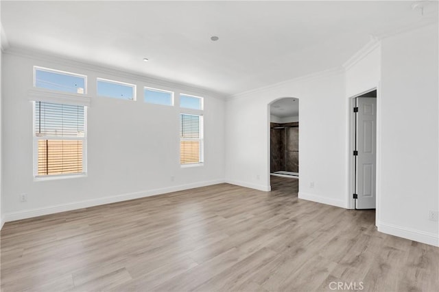 empty room featuring light wood-type flooring, crown molding, and a wealth of natural light