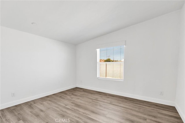 spare room featuring light hardwood / wood-style flooring and lofted ceiling