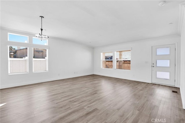 unfurnished living room featuring light wood-type flooring, an inviting chandelier, and crown molding