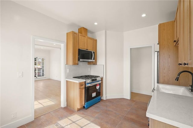 kitchen featuring sink, light brown cabinets, tasteful backsplash, range with gas stovetop, and light tile patterned flooring