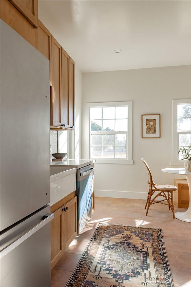 kitchen featuring stainless steel fridge, a healthy amount of sunlight, and light tile patterned floors