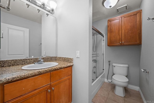 full bathroom with tile patterned floors, vanity, bath / shower combo with glass door, and toilet