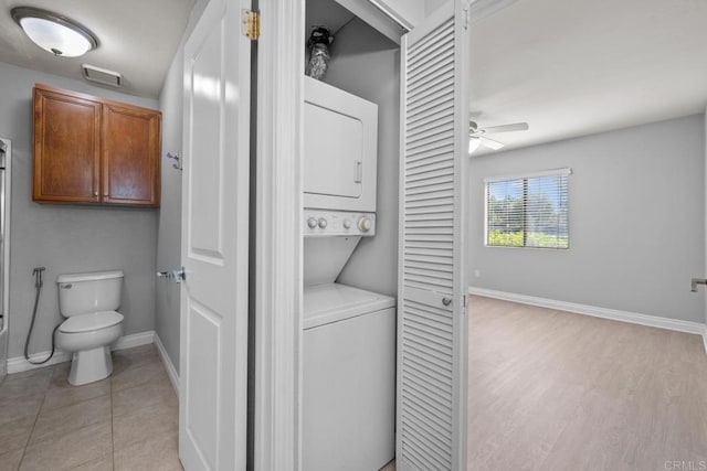 washroom featuring light tile patterned floors, ceiling fan, and stacked washer / drying machine