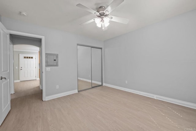 unfurnished bedroom featuring electric panel, a closet, light hardwood / wood-style floors, and ceiling fan