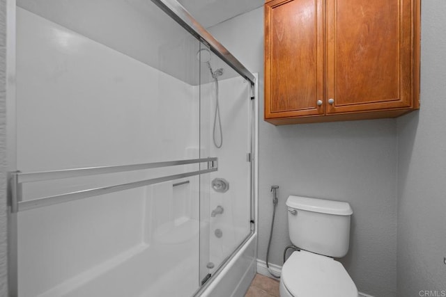 full bath with bath / shower combo with glass door, toilet, and tile patterned floors