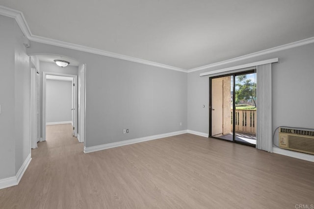 spare room featuring ornamental molding, a wall unit AC, wood finished floors, and baseboards