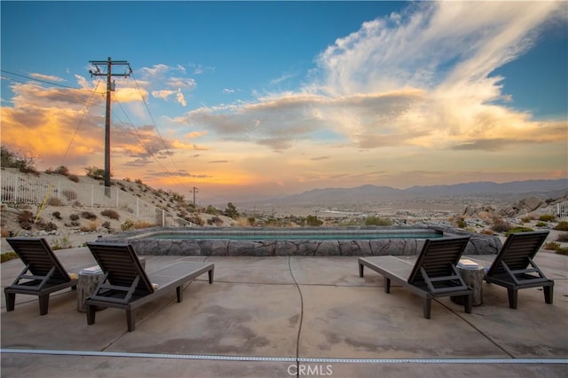 patio terrace at dusk featuring a mountain view