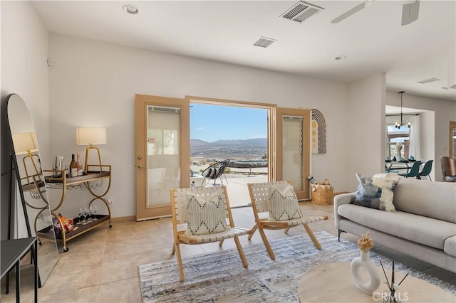 living room with a mountain view, light tile patterned flooring, and ceiling fan with notable chandelier