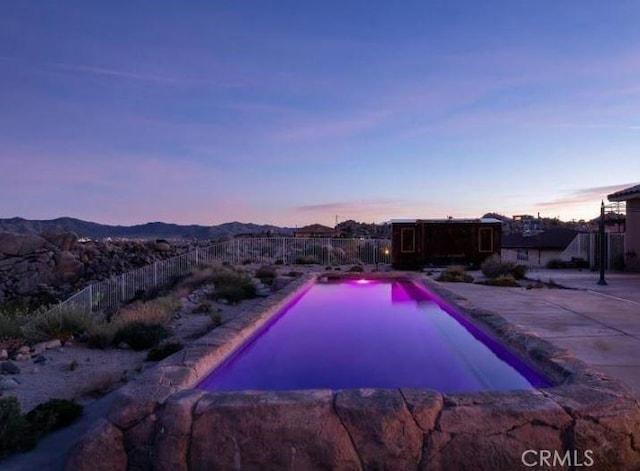 pool at dusk with a mountain view and a patio