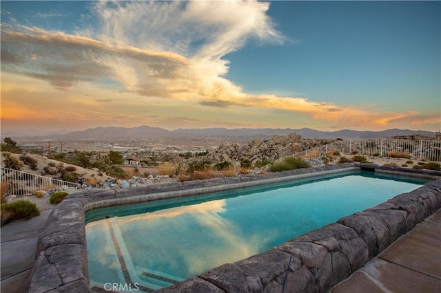 pool at dusk featuring a mountain view