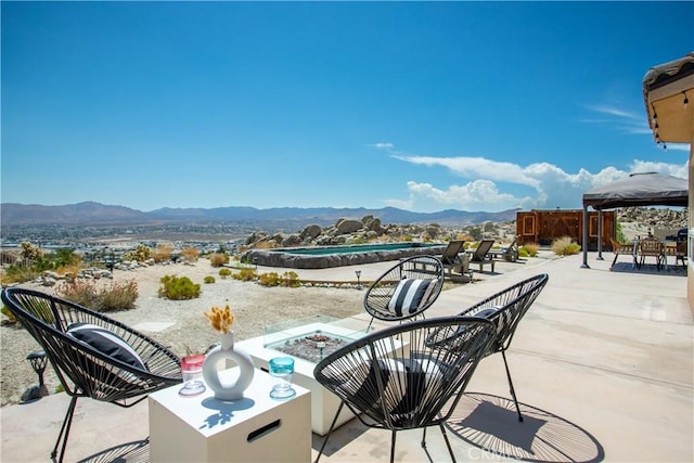 view of patio / terrace with a mountain view and an outdoor fire pit