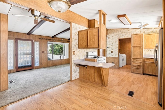 kitchen featuring kitchen peninsula, stainless steel fridge, white gas range, and light hardwood / wood-style floors