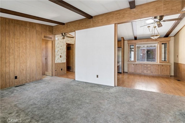 spare room featuring beam ceiling, wooden walls, ceiling fan, and light hardwood / wood-style floors