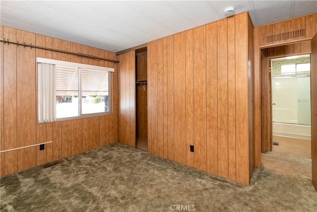 carpeted spare room with wood walls