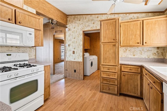 kitchen with vaulted ceiling, wood walls, white appliances, and light wood-type flooring