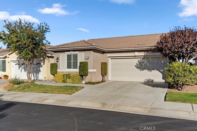 single story home with a tile roof, concrete driveway, a garage, and stucco siding