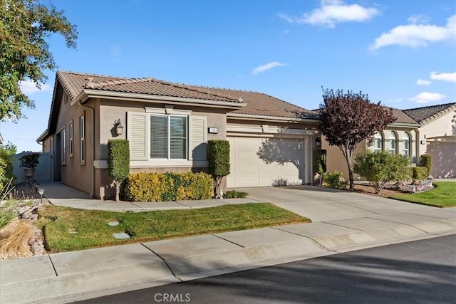 view of front facade with stucco siding, concrete driveway, an attached garage, and a tile roof