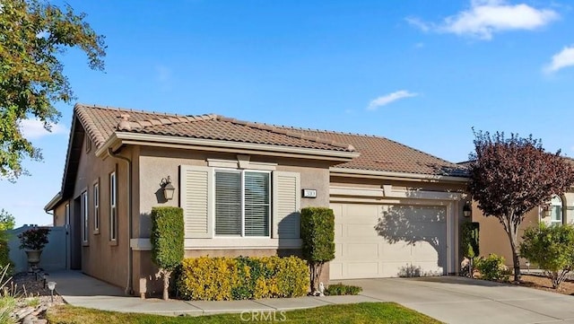 view of front of house with a tile roof, an attached garage, driveway, and stucco siding