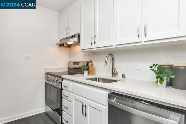 kitchen with sink, appliances with stainless steel finishes, white cabinetry, backsplash, and light stone countertops