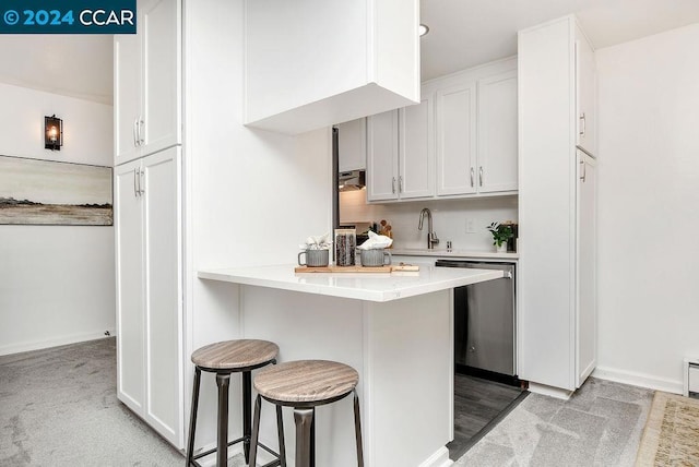 kitchen with dishwasher, sink, white cabinets, a kitchen bar, and kitchen peninsula