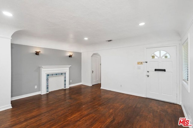 unfurnished living room featuring a textured ceiling and dark hardwood / wood-style floors