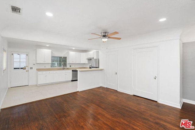 kitchen with dark wood-type flooring, sink, appliances with stainless steel finishes, white cabinetry, and kitchen peninsula