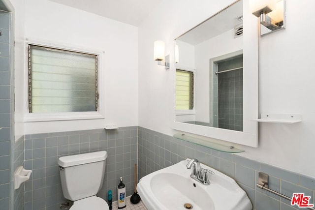 bathroom with sink, tile walls, and toilet