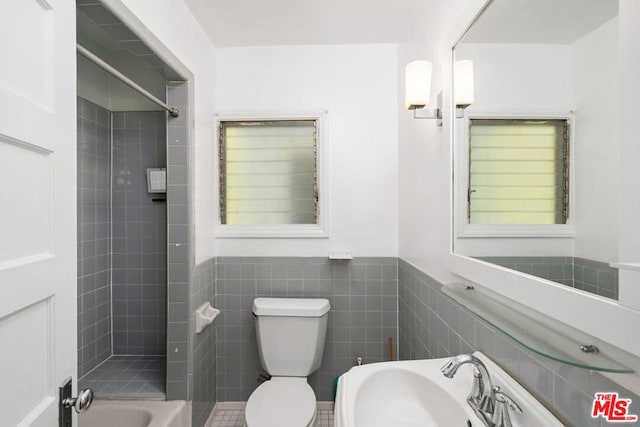 bathroom with toilet, tile walls, and sink