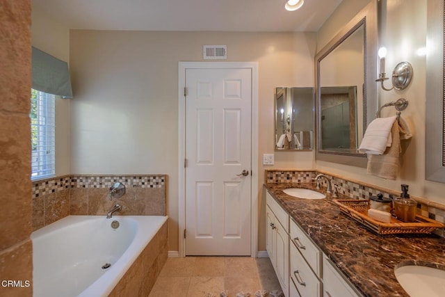 bathroom with vanity, a relaxing tiled tub, and tile patterned floors