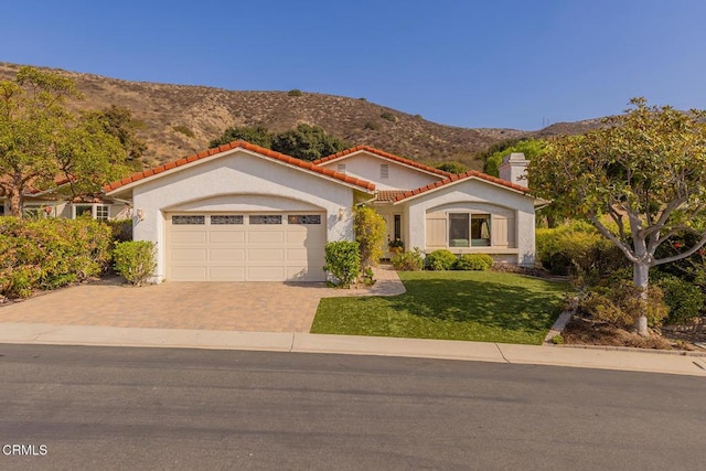 mediterranean / spanish house featuring a mountain view, a garage, and a front lawn