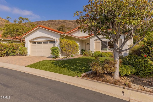 view of front of house with a mountain view, a front yard, and a garage