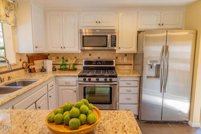 kitchen featuring decorative backsplash, white cabinetry, sink, and stainless steel appliances