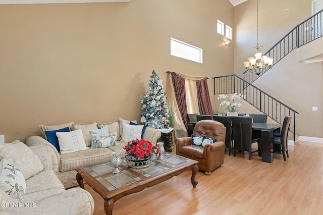 living room with a towering ceiling, a chandelier, and hardwood / wood-style flooring