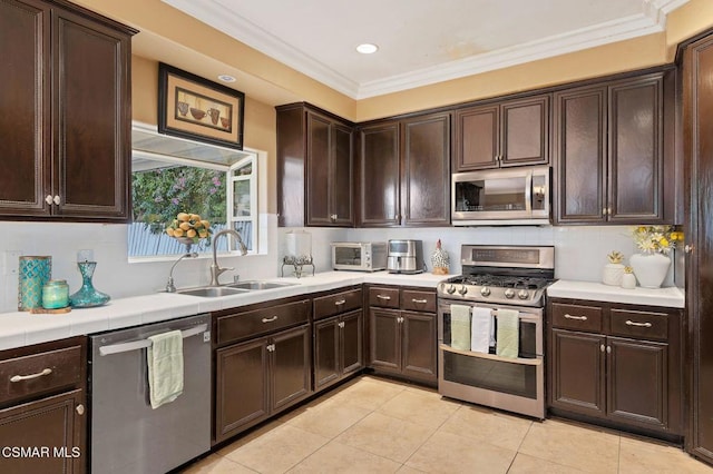 kitchen with ornamental molding, appliances with stainless steel finishes, sink, and dark brown cabinetry