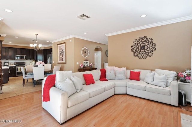 living room featuring ornamental molding, an inviting chandelier, and light hardwood / wood-style floors