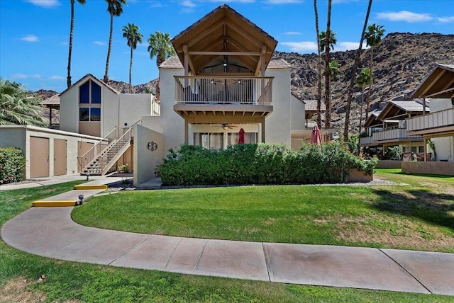 view of front of house featuring ceiling fan, a storage unit, a balcony, and a front lawn