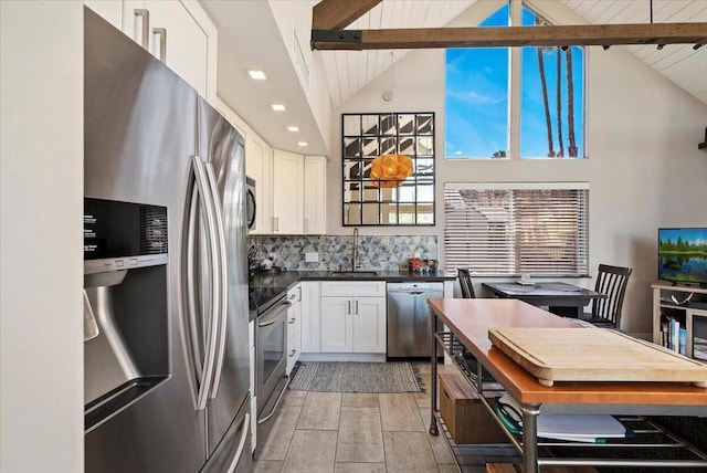 kitchen with appliances with stainless steel finishes, decorative backsplash, beamed ceiling, white cabinets, and sink