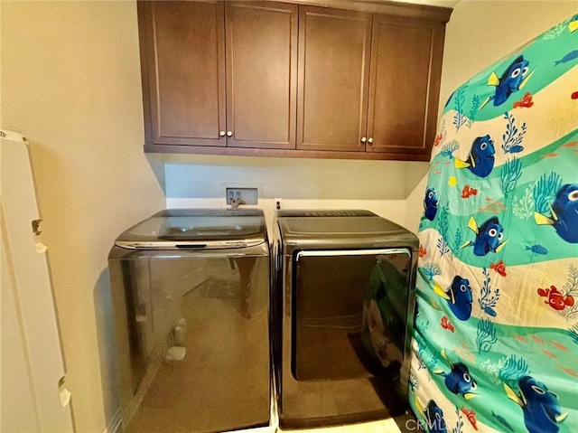 clothes washing area with washer and dryer and cabinets