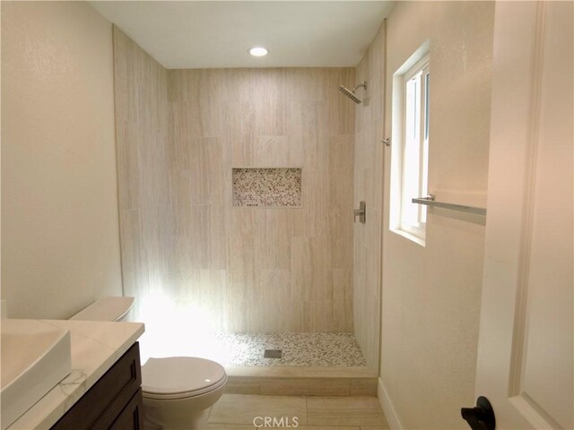 bathroom featuring vanity, toilet, and a tile shower