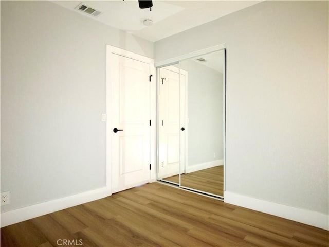 unfurnished bedroom with hardwood / wood-style floors, ceiling fan, and a closet