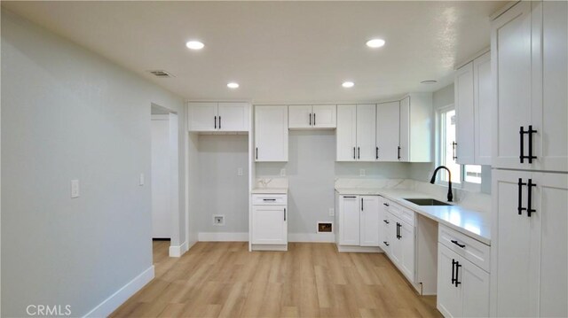 kitchen with white cabinets, light hardwood / wood-style floors, and sink