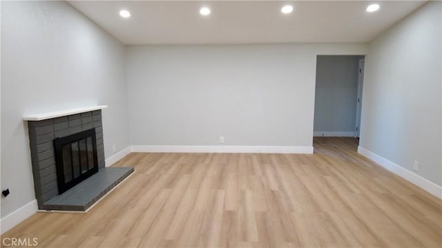 unfurnished living room with light hardwood / wood-style floors and a brick fireplace