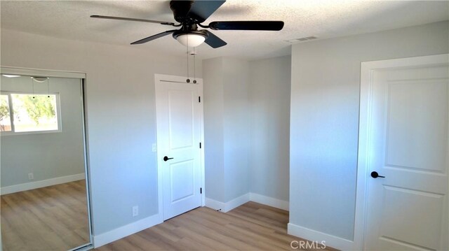 unfurnished bedroom featuring ceiling fan, light hardwood / wood-style flooring, and a textured ceiling