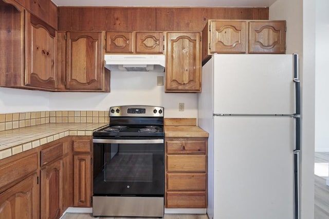 kitchen with stainless steel electric range, tile countertops, and white refrigerator