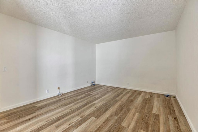 spare room featuring a textured ceiling and light hardwood / wood-style floors