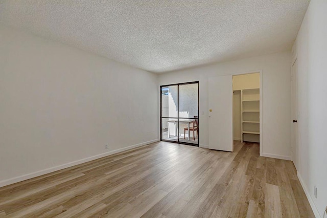 empty room with a textured ceiling and light hardwood / wood-style floors